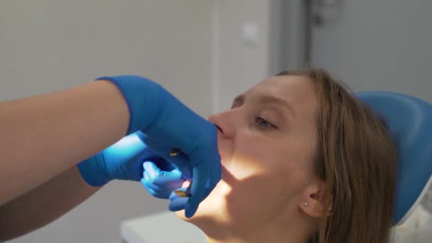 De orthodontist snijdt de beugel in de mond van de patiënt. De dokters hebben rubberen handschoenen aan. In de handen van een metalen werktuig. Ze bijt de draad er voorzichtig af. Beugels — Stockvideo