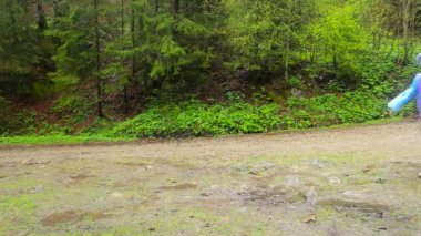 Sırt çantalı bir grup arkadaş yağmurlu havada ormanda peş peşe yürürler. Koşun!