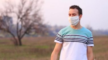 Sağlık maskeli genç adam tecrit sırasında dışarıda telefonla selfie çekiyor.
