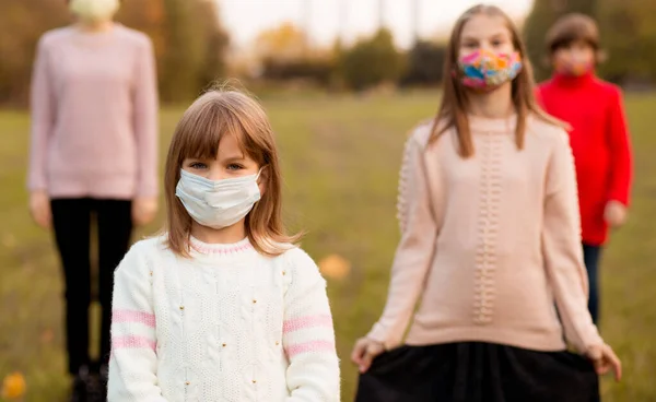 Kerumunan anak-anak berjalan dalam pelindung masker medis di jalan selama epidemi coronavirus. Konsep gaya hidup baru anak-anak dengan wajah tertutup. Fokus selektif — Stok Foto