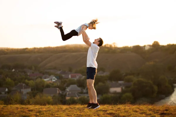 Famiglia attiva. Padre e figlia si divertono insieme. Papà getta la figlia in cielo. — Foto Stock