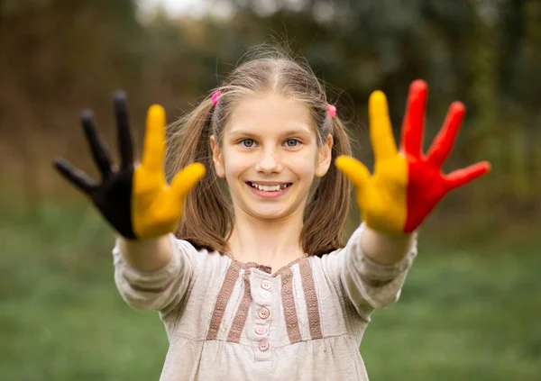 Feliz retrato de niña con las manos pintadas en colores de bandera de Bélgica —  Fotos de Stock