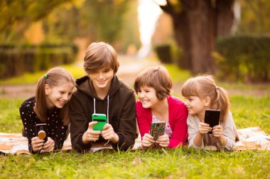 Bir grup kız arkadaş cep telefonu kullanıyor ve sohbet ediyorlar. 