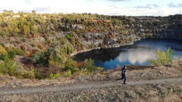 Vue aérienne du jeune homme faisant du jogging sur une colline près d'un lac — Video