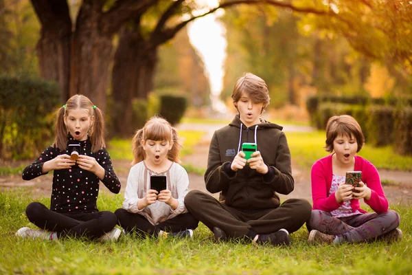 Een groep nieuwsgierige kinderen die samen een mobiel toestel gebruiken. Telefoonverslaving. — Stockfoto