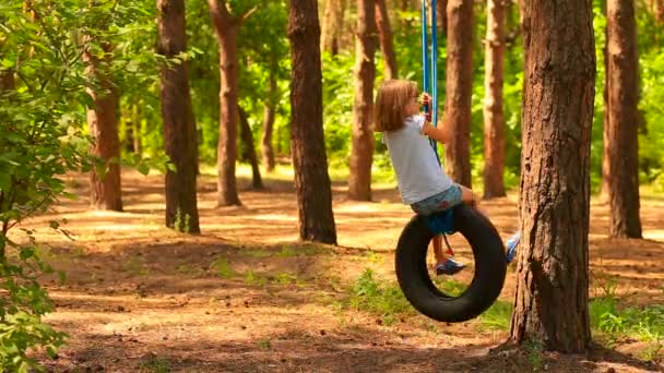 Roztomilé školka dítě dívka houpání na pneumatice houpačka v letním parku — Stock video