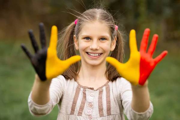 Feliz retrato de niña con las manos pintadas en colores de bandera de Bélgica —  Fotos de Stock