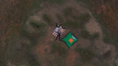 Genç ailenin genel görünüşü çadırın yanındaki battaniyeye uzanıyor ve birlikte kamp tatilinin tadını çıkarıyor.