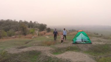 Mutlu gezgin ailesinin hava manzarası dağların kenarındaki çadır kampı yakınlarında boş zamanların ve özgürlüğün tadını çıkarıyor.