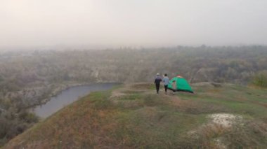 Mutlu gezgin ailesinin hava manzarası dağların kenarındaki çadır kampı yakınlarında boş zamanların ve özgürlüğün tadını çıkarıyor.
