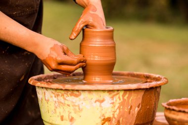 Çömlekçinin elleri seramik kavanozu çömlek çarkının üzerinde yapar.