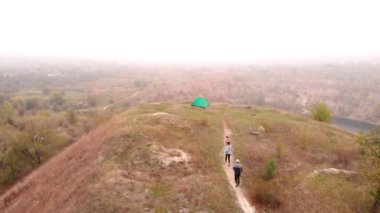 Mutlu gezgin ailesinin hava manzarası dağların kenarındaki çadır kampı yakınlarında boş zamanların ve özgürlüğün tadını çıkarıyor.