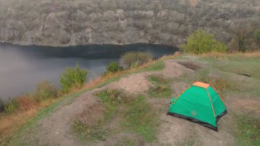 Mutlu gezgin ailesinin hava manzarası dağların kenarındaki çadır kampı yakınlarında boş zamanların ve özgürlüğün tadını çıkarıyor.