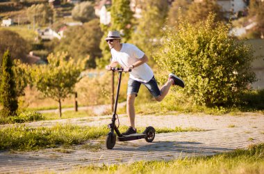 Şehir parkında güneş gözlüklü ve şapkalı neşeli bir adam.