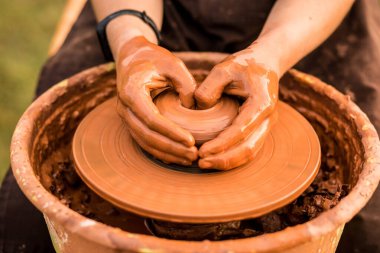 Çömlek çarkında çalışan ve dışarıda kil çömlek yapan adamın yakın çekimi.