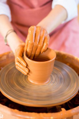 Eller kilden kupa yontuyor. Çömlekçi çarkında modellik atölyesi.