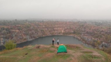 Aktif ailenin kamp gezisindeki hava aracı görüntüsü. Gölün yanındaki tepede rahatlayın.