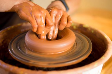 Çömlekçinin elleri çömlekçi çarkında çanak çömlek yapar. Atölyedeki heykeltraş kil ürün yapıyor