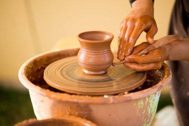Çömlekçinin elleri çömlekçi çarkında çanak çömlek yapar. Atölyedeki heykeltraş kil ürün yapıyor