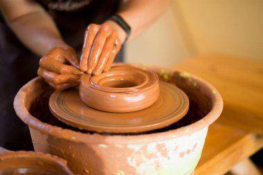 Çömlekçinin elleri çömlekçi çarkında çanak çömlek yapar. Atölyedeki heykeltraş kil ürün yapıyor
