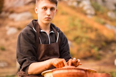 Çömlekçi adam kil kaplama ile çalışır. Doğa geçmişi olan genç bir çömlekçi.