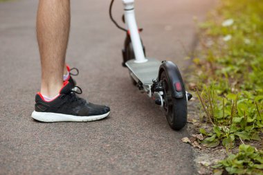 Şık kıyafetli bir adamın sokak ortasında elektrikli scooter üzerinde çekilmiş fotoğrafı.