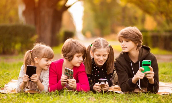 Akıllı telefon bağımlısı bir grup çocuk dijital tablette film karikatürü izliyorlar. Çocuklar birlikte telefonla oynuyorlar.