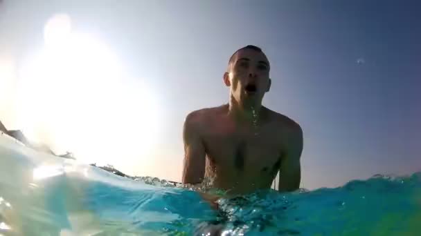 Homem ativo feliz pulando sob a água com os olhos abertos na piscina e fazer auto vídeo na câmera de ação. Férias — Vídeo de Stock