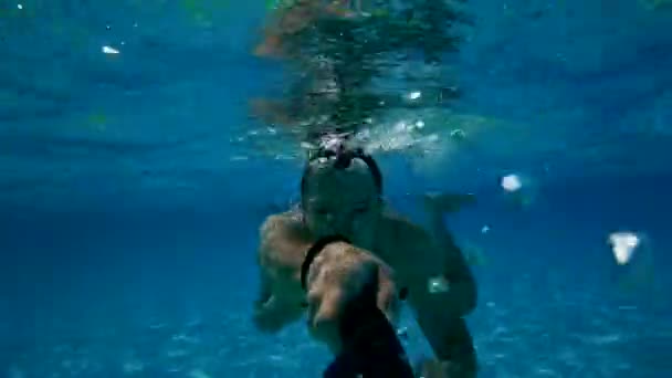 Szczęśliwy aktywny człowiek skacze pod wodą z otwartymi oczami w basenie i zrobić własny film na kamerze akcji. Wakacje — Wideo stockowe
