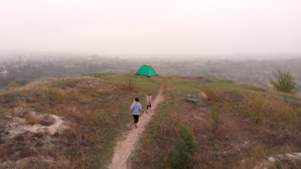 Flygfoto över glad resenär familj promenad nära tält läger vid fjäll sjö njuta av fritid och aktiv tid tillsammans — Stockvideo