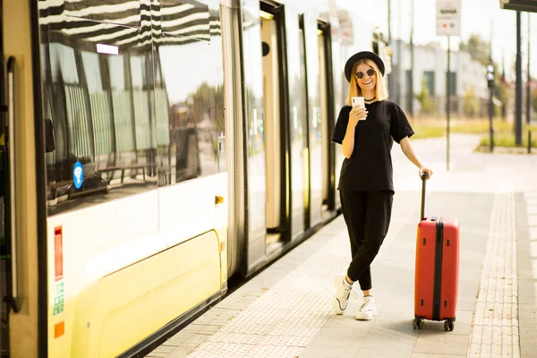Femme touristique utiliser téléphone intelligent avec valise et porter noir total. Traveller girl appeler taxi sur la gare — Photo