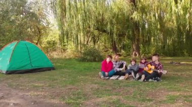 Çocuklu mutlu bir aile yaz tatilinde kamp yaparken şarkı söyler. Arkadaşlar eğlenirken akustik gitar çalan bir adam. 