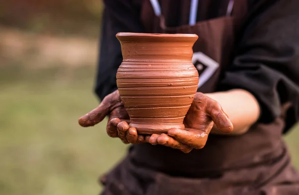 Руки гончара держат глиняный горшок на мастерской — стоковое фото