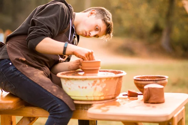 Людина-гончар працює з глиняним посудом. Молодий чоловік гончар на своїй майстерні з фоном природи — стокове фото