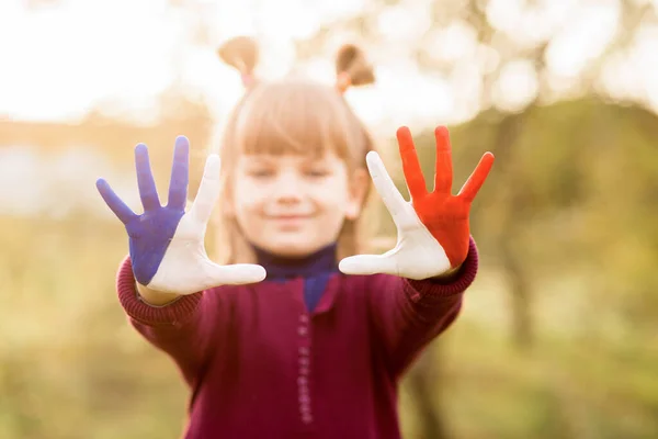 Chica alegre agitando las manos pintadas en colores de la bandera de Francia y decir hola al aire libre al atardecer —  Fotos de Stock