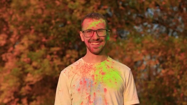 Joyful bebaarde man met bril in uitstekende stemming in holi kleuren op festival — Stockvideo