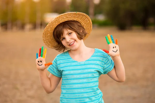 Gelukkig glimlachen klein meisje met de handen geschilderd in grappig gezicht spelen buiten in park. — Stockfoto