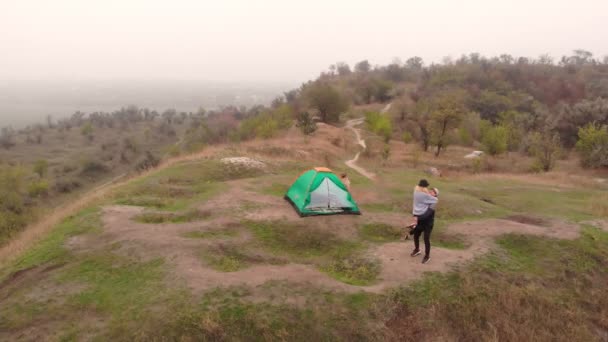 Aktivt familjeresekoncept. Flygfoto av unga föräldrar med barn dotter promenader nära camping tält med upphöjda händer medan vandring tillsammans — Stockvideo