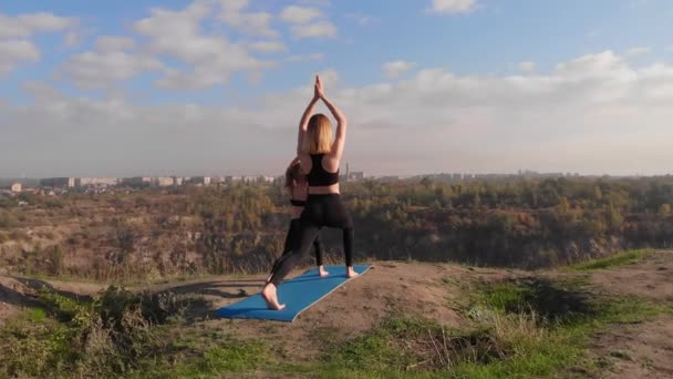 Familie Pilates Training zusammen. Die junge Mutter und ihre kleine Tochter machen morgens Dehnübungen auf dem Hügel. Sporterziehung und Entwicklung der Kinder — Stockvideo