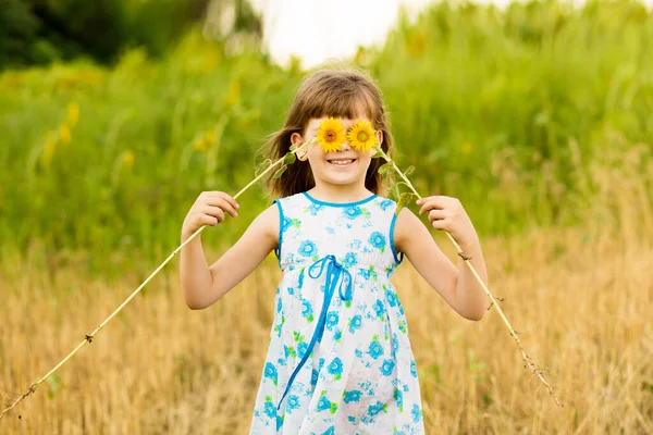 Menina feliz jogar no campo e fazer olhos girassóis engraçados. Boas festas — Fotografia de Stock