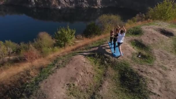 Omloppsbana flygfoto av familj om tre, mor far och dotter, göra yoga övningar på toppen av backen på solig morgon. Ung familj utbildning långt från rörelse i staden, föregå med gott exempel och ingjuta i — Stockvideo