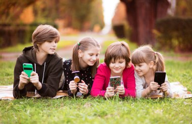 Akıllı telefon bağımlısı bir grup çocuk dijital tablette film karikatürü izliyorlar. Çocuklar birlikte telefonla oynuyorlar.