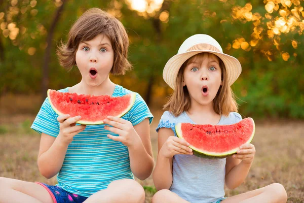 Adorables niñas con cara de maravilla y con sandía en las manos pensar en la pregunta, reflexivo acerca de la idea confusa Fotos De Stock