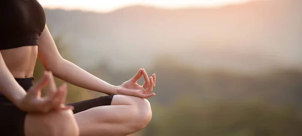 Primer plano con enfoque selectivo de manos mujer sentada en yoga loto posan al aire libre al amanecer, meditando para el equilibrio. Vista horizontal del banner para el diseño del encabezado del sitio web con espacio de copia — Foto de Stock