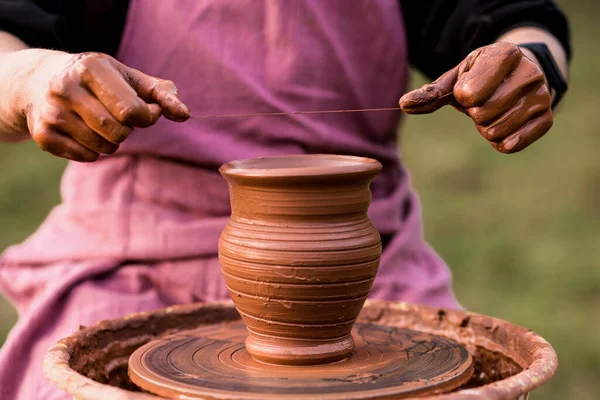 Job is done. Young pottery man with finished handmade clay product. Professional male potter work with clay on pottery wheel in workshop. Handmade, small business, crafting work concept. Ceramist