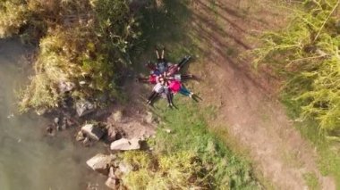 Havadan aşağıya insansız hava araçları yıldız gibi çimenlerin üzerinde uzanan insanları gösteriyor. Arkadaşlar göl kenarındaki bahar parkında birlikte iyi vakit geçiriyorlar.