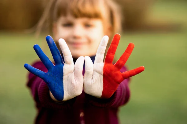 Radosna dziewczyna macha rękami pomalowane we Francji flagi kolorów i powiedzieć cześć zewnątrz o zachodzie słońca — Zdjęcie stockowe