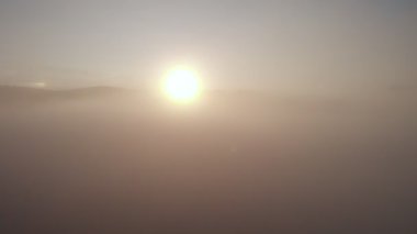 Bulutların ve gökyüzünün üzerinde sabah güneşinin doğuşu için harika bir hava aracı görüntüsü. Dağların tepesinde bulutlar arasında uçuyor. Güzel günbatımı dağ sırtı