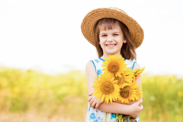 Retrato al aire libre de adorable niña en sombrero de paja y vestido azul está caminando en un campo de girasoles, reuniendo y recogiendo ramo. Vacaciones de verano —  Fotos de Stock