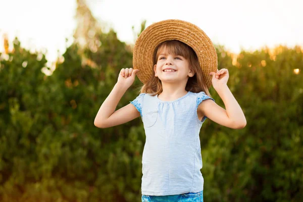 Adorable niña en sombrero de paja pasar tiempo al aire libre en el día de verano. Feliz retrato de niño tímido sonriente —  Fotos de Stock